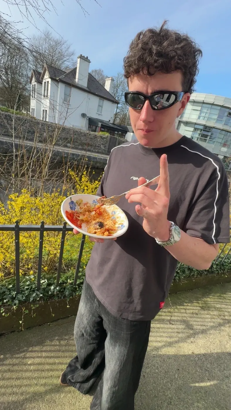 Sylvan in sunglasses eating lunch outdoors by a river